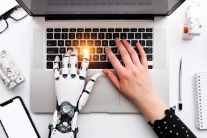 Lo spazio didattico è sempre più modellato rispetto alle esigenze di una formazione professionale immersiva, che si avvale di strumenti pratici e laboratoriali. Nella foto, due mani, una robotica una biologica, sulla tastiera di un pc.