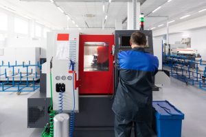 Possiamo considerare la programmazione CNC come il fulcro dell'industria moderna: è la tecnologia che più di ogni altra muove e determina la produzione industriale in questo momento. Nella foto, un operatore al lavoro con una macchina utensile.
