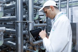 I sistemi idraulici industriali richiedono regolari controlli e manutenzione. Nella foto, un tecnico che misura la pressione del fluido che circola all'interno di un condotto industriale.
