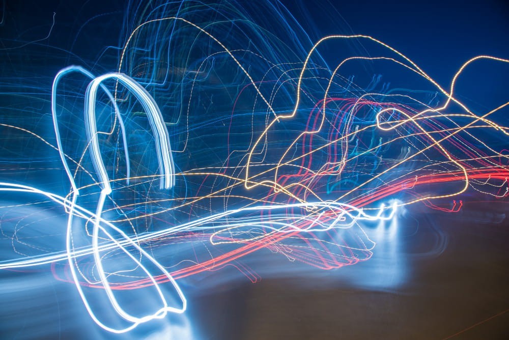 Scie luminose blu, dorate e rosse che si intrecciano nel buio, a rappresentare il flusso della corrente elettrica nei circuiti moderni.